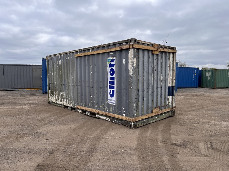 Side view of a worn 20ft shipping container with surface damage and branded Elliott decals