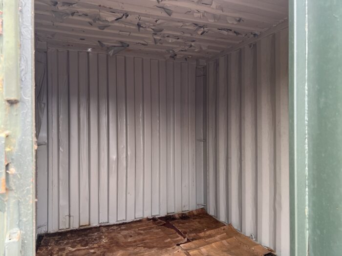 Interior of 8ft green storage container showing metal walls and wooden floor