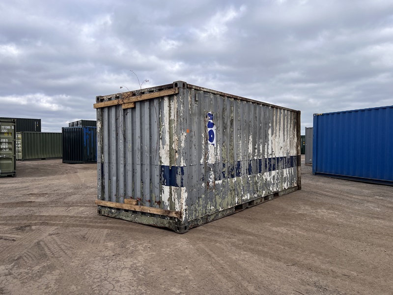 Back corner of a battered 20ft container with peeling grey and blue paint stripes