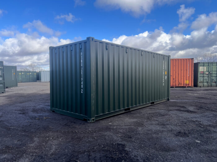 Dark green 20ft shipping container on gravel surface under blue sky, ideal for secure storage or commercial use.