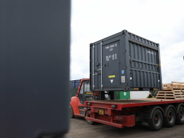 10ft kiosk container being loaded onto a flatbed vehicle using forklift at Parsons Containers depot